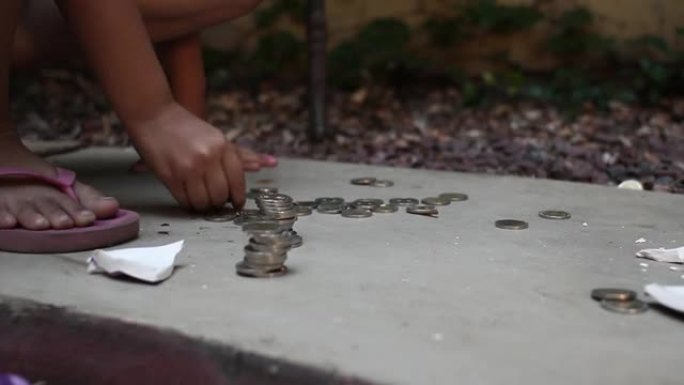 一个小女孩的手在户外从她破碎的存钱罐里收集硬币。特写。