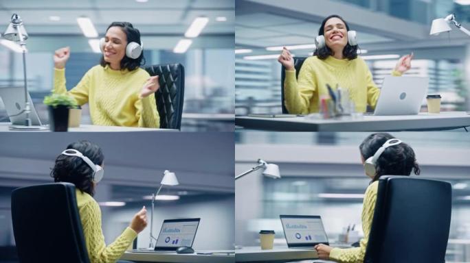 360学位办公室: 微笑的西班牙裔女商人坐在办公桌前在电脑上工作，戴着耳机，听音乐，跳舞。她很快乐，