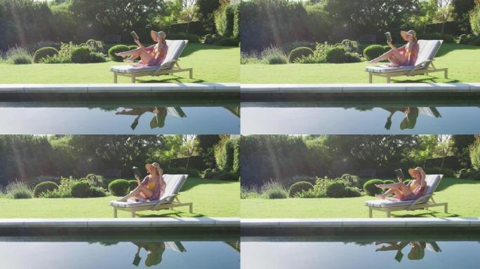 白人妇女在花园里的躺椅上晒日光浴时看书