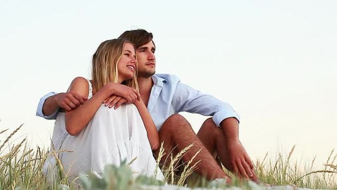 相爱的年轻夫妇一起坐在海滩上