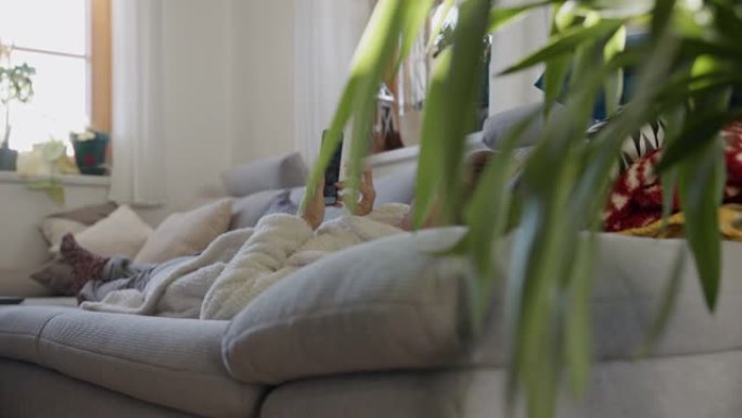 一个女人用电话特写，穿着浴袍放松，躺在沙发上