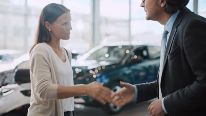 SLO MO汽车推销员握手并将新车钥匙交给女顾客