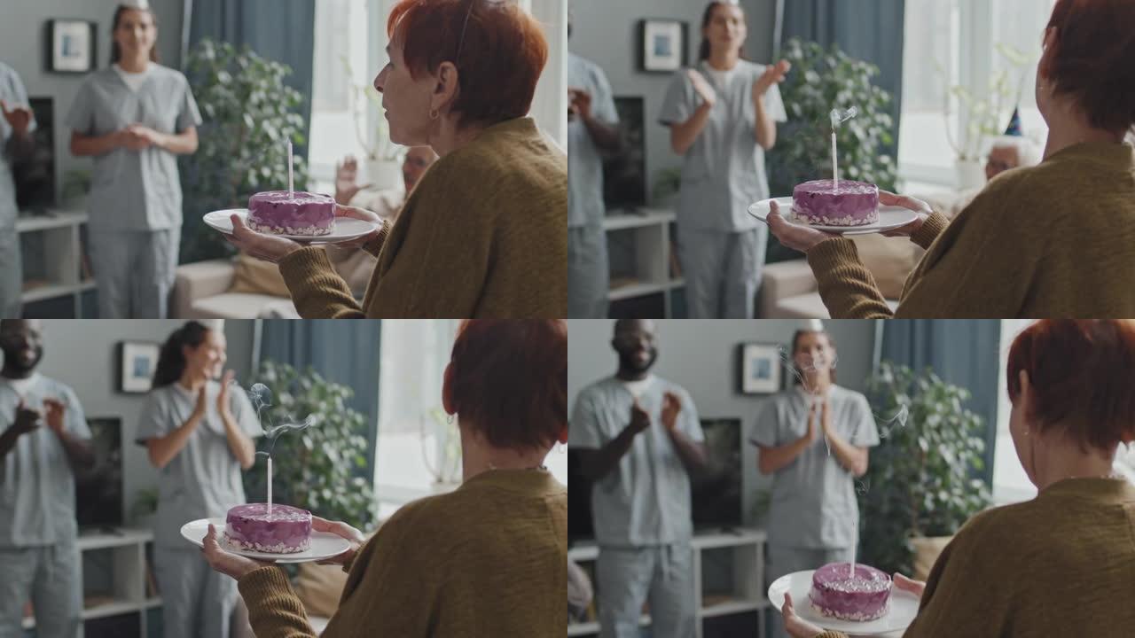 高级妇女在生日蛋糕上吹蜡烛