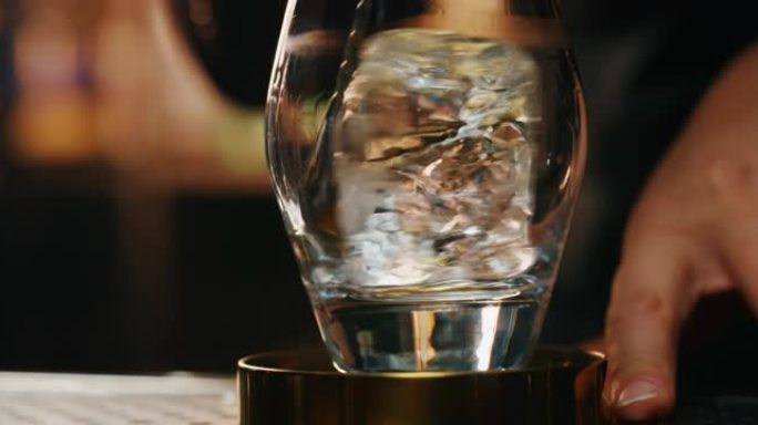 专业调酒师的特写镜头是在酒吧或迪斯科俱乐部为顾客准备酒精鸡尾酒的同时，将专业水晶持久冰块混合在玻璃杯