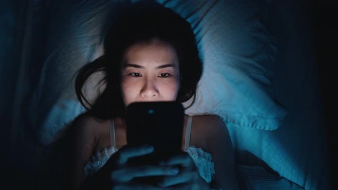 女人晚上在床上使用智能手机