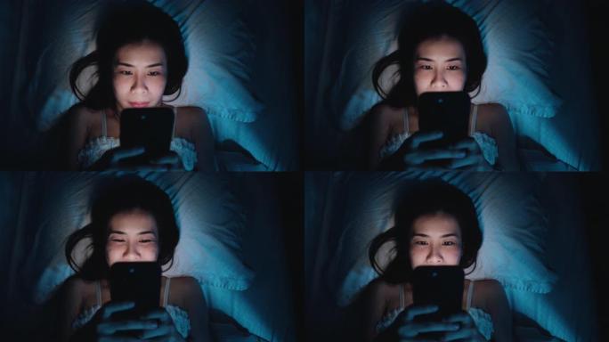 女人晚上在床上使用智能手机