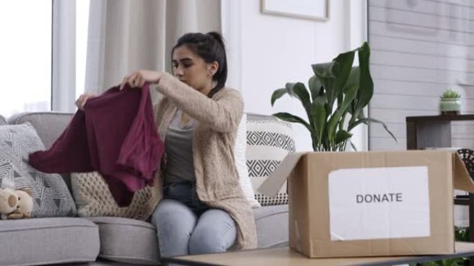 4k视频片段，一名妇女在家里的捐款箱中包装物品