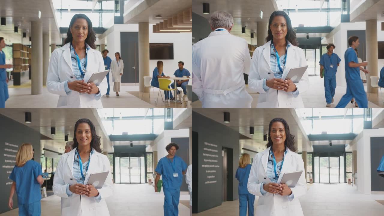 在繁忙的医院大楼中穿着白色外套和数字平板电脑的女医生肖像