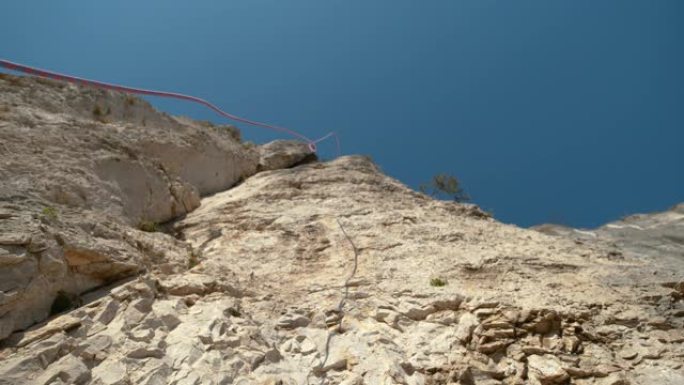 自下而上，dop: 蓝色和红色的绳索从高耸的悬崖顶部掉落。