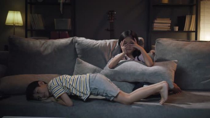 亚洲家庭兄弟姐妹在晚上在家观看直播激动的疤痕或恐怖电影。自由时间电视节目时间。