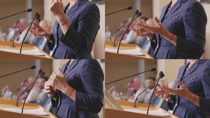 女政治家在大会上讲话时，双手在打手势