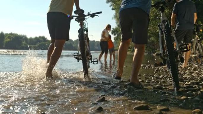 SLO MO一家带三个孩子在河水浅水区推自行车