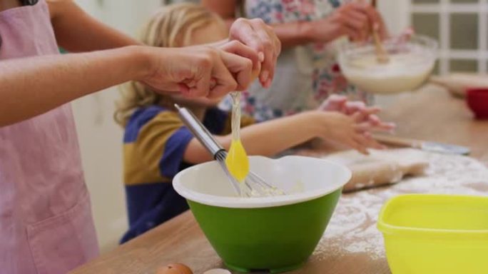 高加索母亲的中段在厨房烘烤儿子和女儿将鸡蛋打入碗中