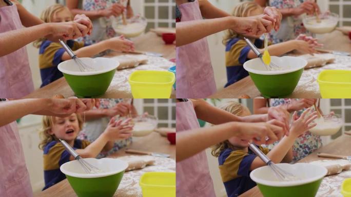 高加索母亲的中段在厨房烘烤儿子和女儿将鸡蛋打入碗中