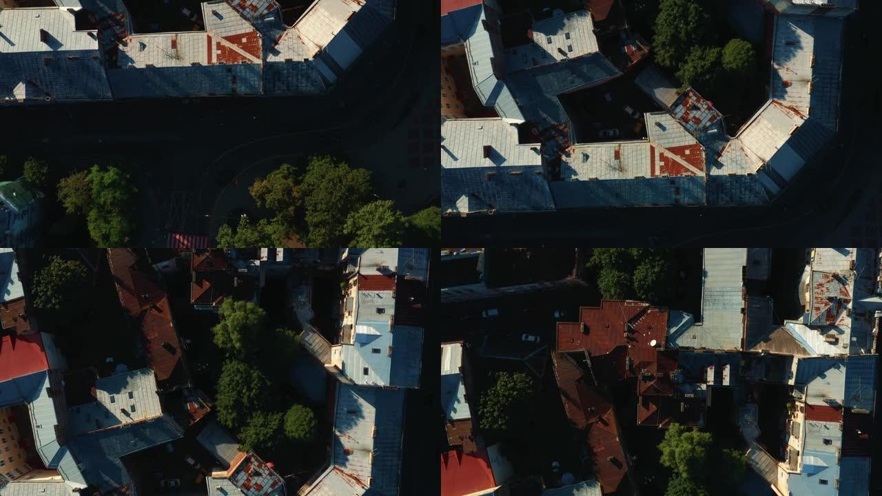 俯视图，无人机在日出时直接飞在乌克兰利沃夫老城的老历史建筑生锈的屋顶和树木上方。
