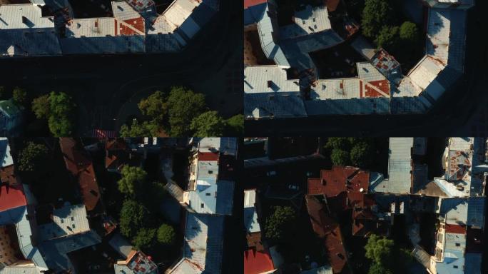 俯视图，无人机在日出时直接飞在乌克兰利沃夫老城的老历史建筑生锈的屋顶和树木上方。