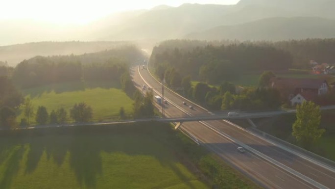 无人机: 日出照亮了通勤者在乡村高速公路上来回行驶。