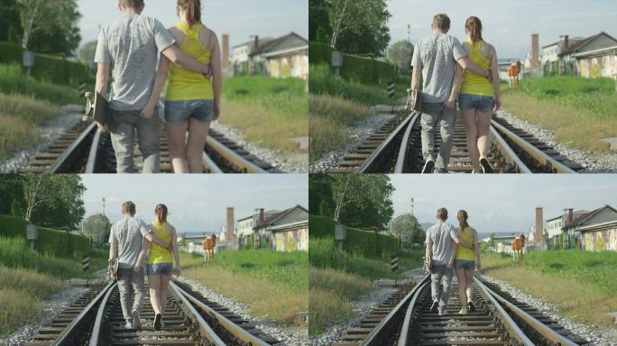 慢动作: 恋爱中的年轻夫妇在铁轨上行走