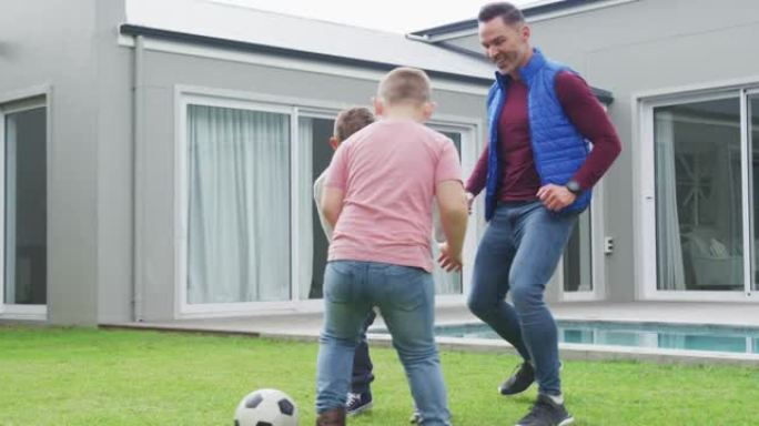 快乐的高加索父亲和两个儿子在花园里踢足球