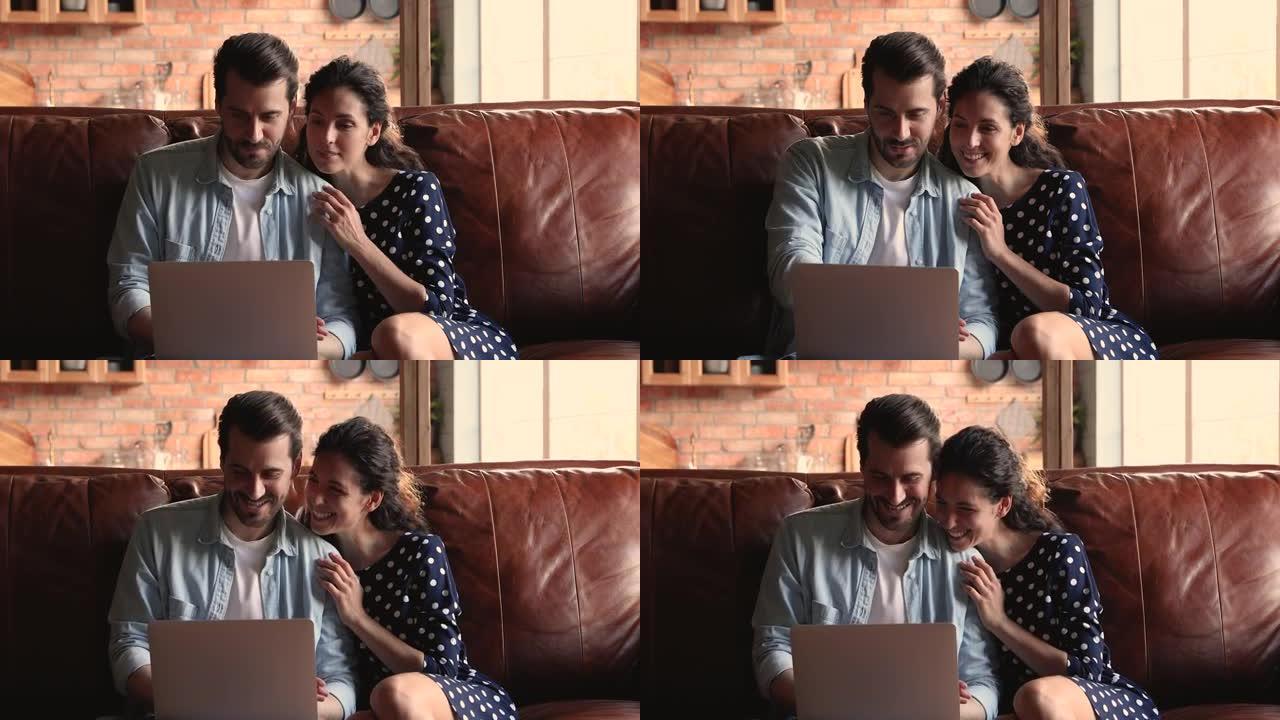 已婚夫妇坐在沙发上，用笔记本电脑讨论在线购买