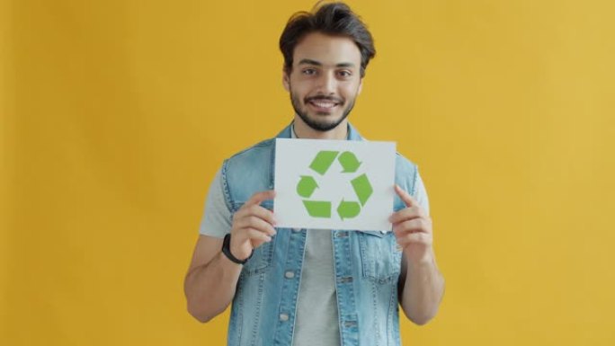 开朗的印度小伙子手持回收标志促进生态保护和微笑