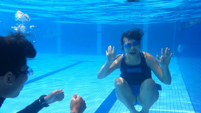 亚洲华裔熟女与教练在水中练习呼吸运动