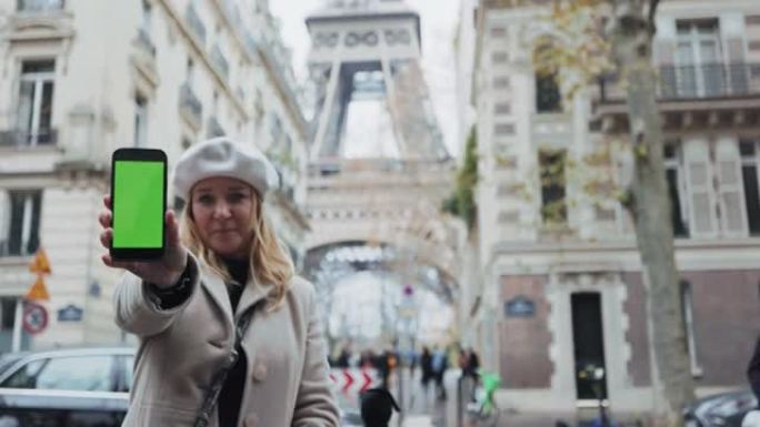 WS魅力四射的法国女人在埃菲尔铁塔旁的街道上展示了她的智能手机，绿屏