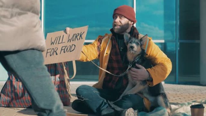 一个带着狗的无家可归的人正在展示一个 “将为食物而工作” 的盘子