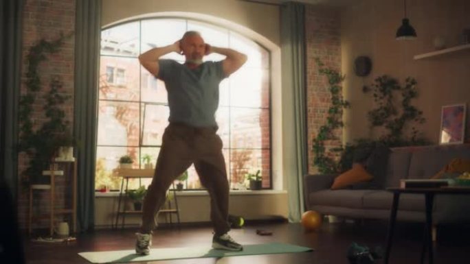 强壮的运动健康的高级男子在阳光明媚的公寓在家晨练时做有氧高膝盖和核心强化练习。健身和娱乐概念。