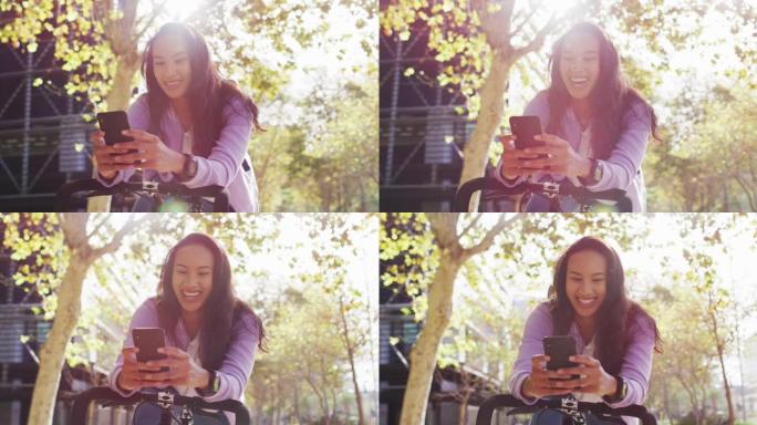 在公园里使用智能手机时，带着自行车微笑的亚洲妇女