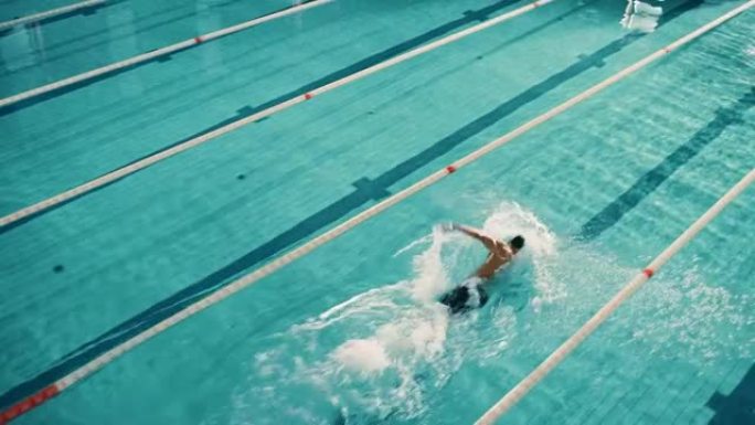 男性游泳运动员潜水，跳进游泳池。专业运动员在锦标赛上表演，使用前爬行，自由泳技术。空中顶部Vew高角