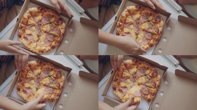 手从纸板箱里拿披萨片的俯视图。