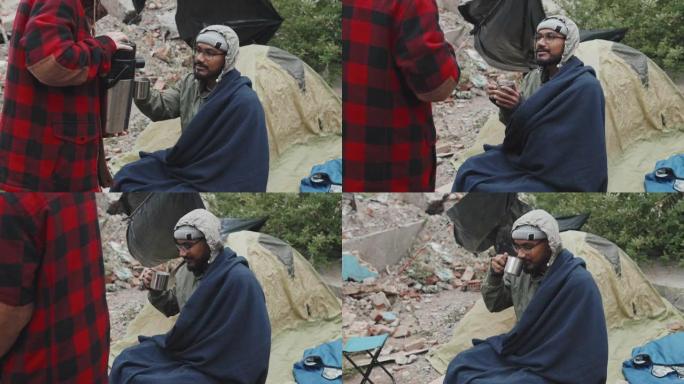 难民男子在帐篷外喝热茶