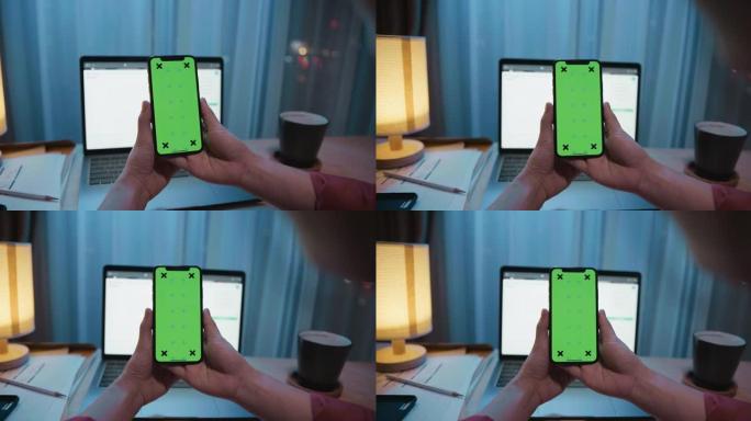 女人在带有绿屏模型的笔记本电脑上使用手机拍摄的照片