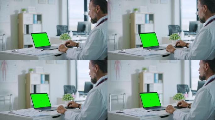 快乐微笑的家庭医生正在一家诊所的电脑上工作。穿着白大褂的医生正在医院办公室的桌子后面浏览病史。