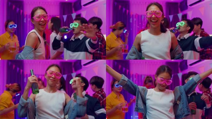 多元群体多民族年轻的亚洲朋友戴着未来派霓虹灯发光眼镜跳舞和喝酒精啤酒有趣的聚会在客厅晚上室内家庭。