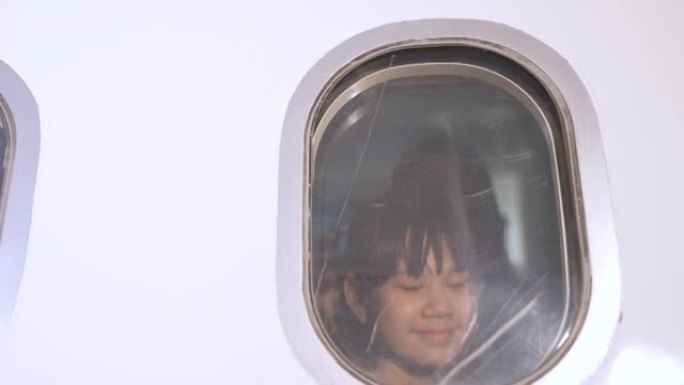 女孩坐在商用飞机上的窗户旁，她坐在窗户旁看着外面的景色。能够乘飞机从飞机外旅行的兴奋。