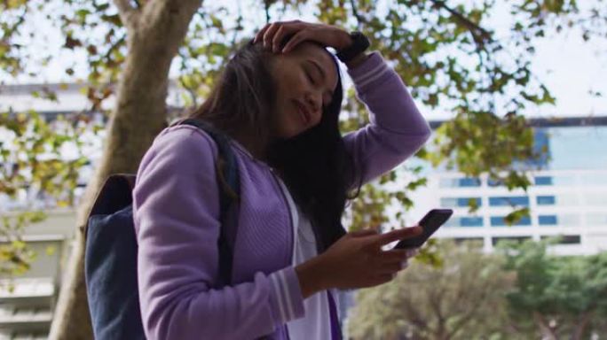 站在公园里使用智能手机时微笑的亚洲妇女