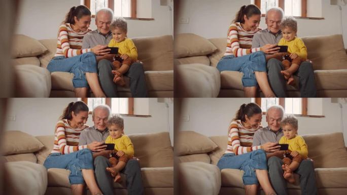 快乐的小家庭聚集在一起，坐在客厅的沙发上，使用智能手机。母亲，儿子和祖父在手机上观看视频并大笑。他们