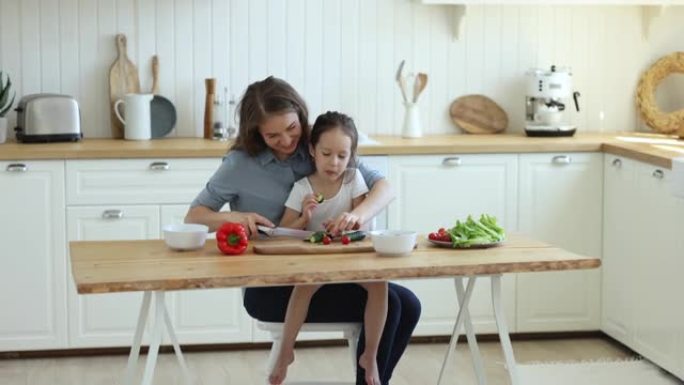 慈爱的母亲在女儿吃黄瓜时准备素食