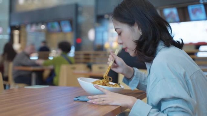 亚洲妇女用筷子吃面条