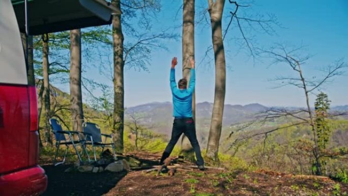 棕色短发的男人早上在大自然中进行健身锻炼，站在大自然的小山上，背景是美丽的风景