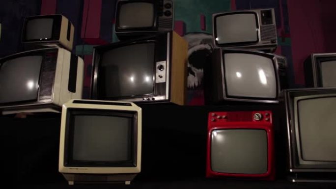 一堆复古电视和一台老式电视打开绿色屏幕。多莉开枪了。