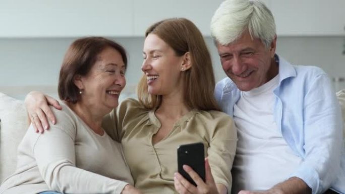 年轻女子和年长的父母在家中使用手机
