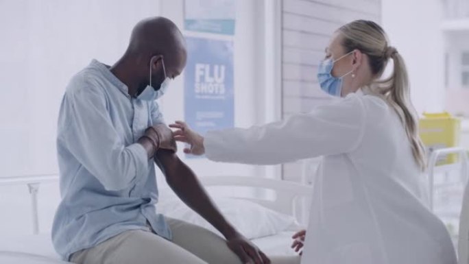 女医生戴着口罩在男性患者的手臂上注射了covid疫苗的注射器。医护人员在诊所接受冠状病毒预防接种后竖