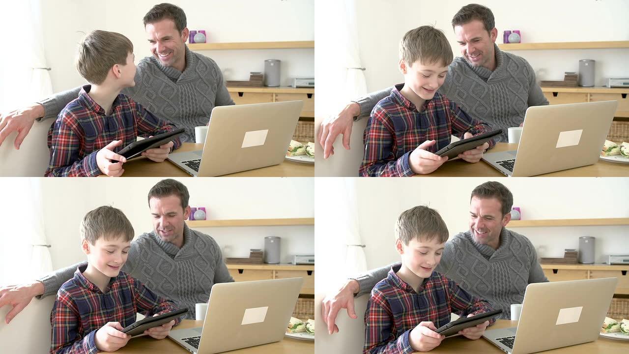 父亲在家里使用笔记本电脑，儿子在家里使用数字平板电脑