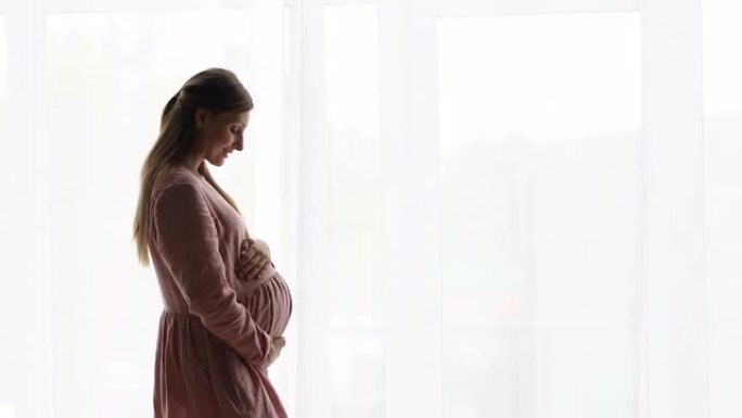 深情的未来妈妈拥抱怀孕的肚子在白色背景上摆姿势