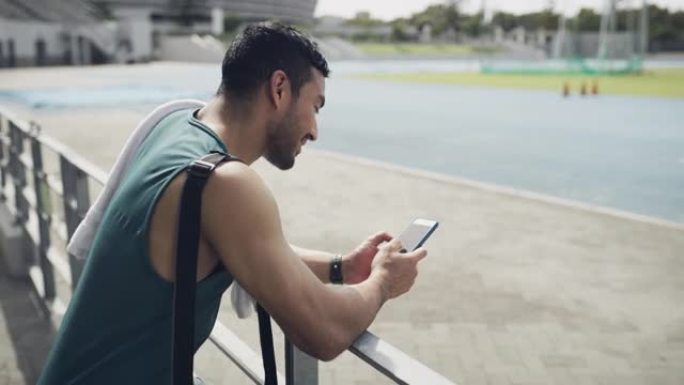 一个年轻人在田径跑道上等待时使用手机的4k视频片段