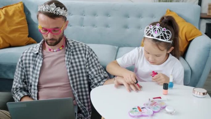 严肃的男人戴着儿童bijouterie和笔记本电脑一起工作，女儿为他修指甲