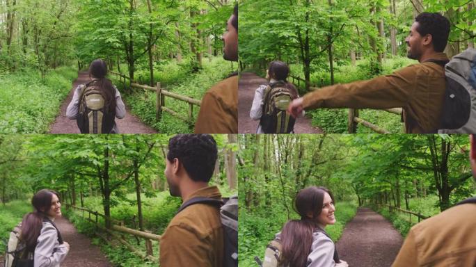 夫妇沿着小路徒步穿越乡村树木的后视图
